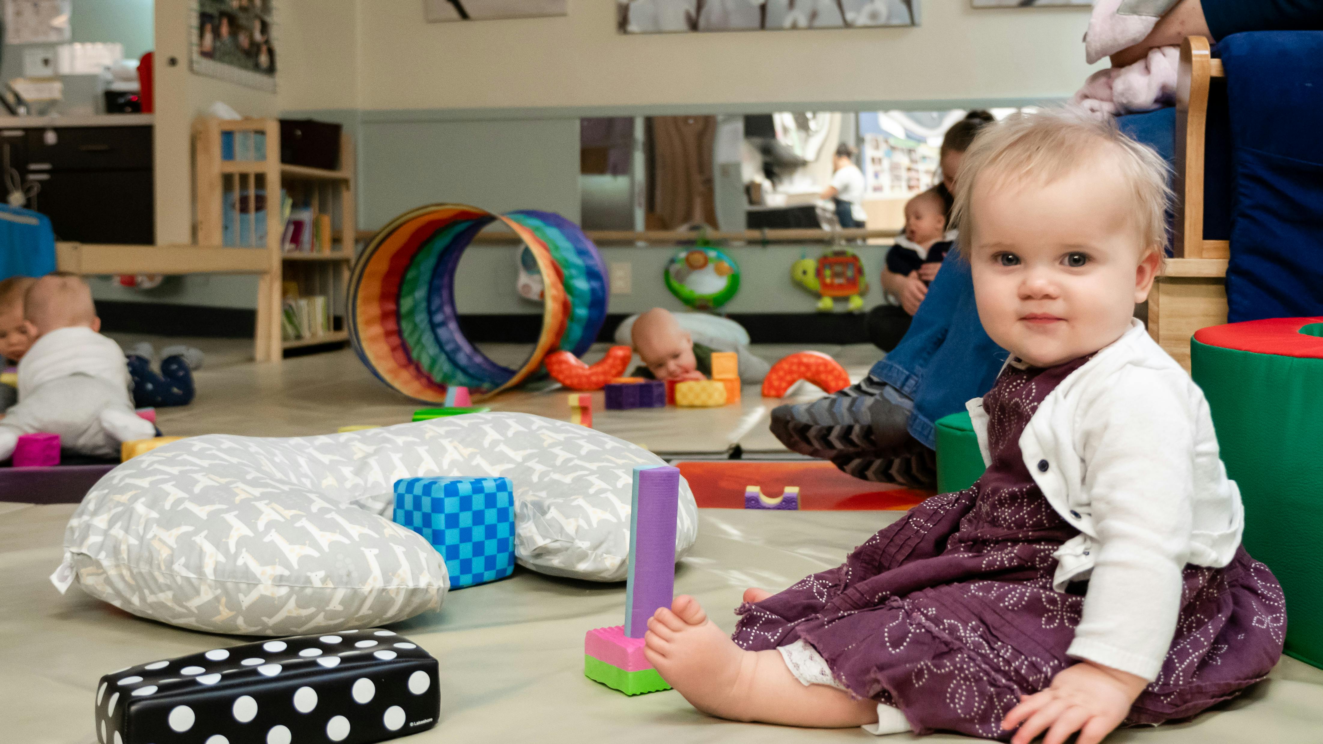 Child sitting on floor with toys in a play area