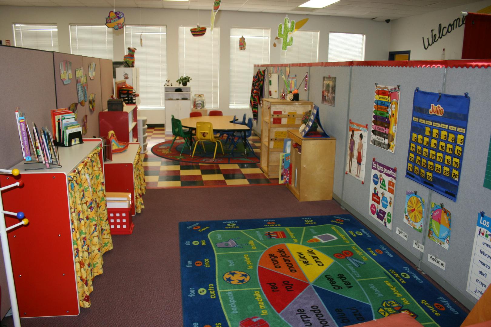 A colorful classroom with a rug, tables, and learning materials