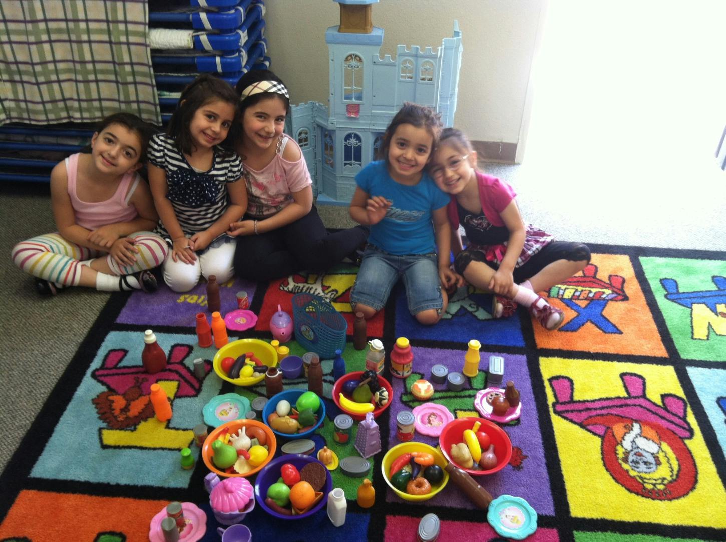 Children playing with toy food on a colorful rug