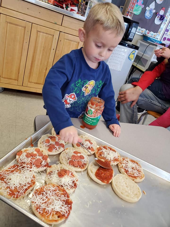 Child making mini pizzas on a baking sheet