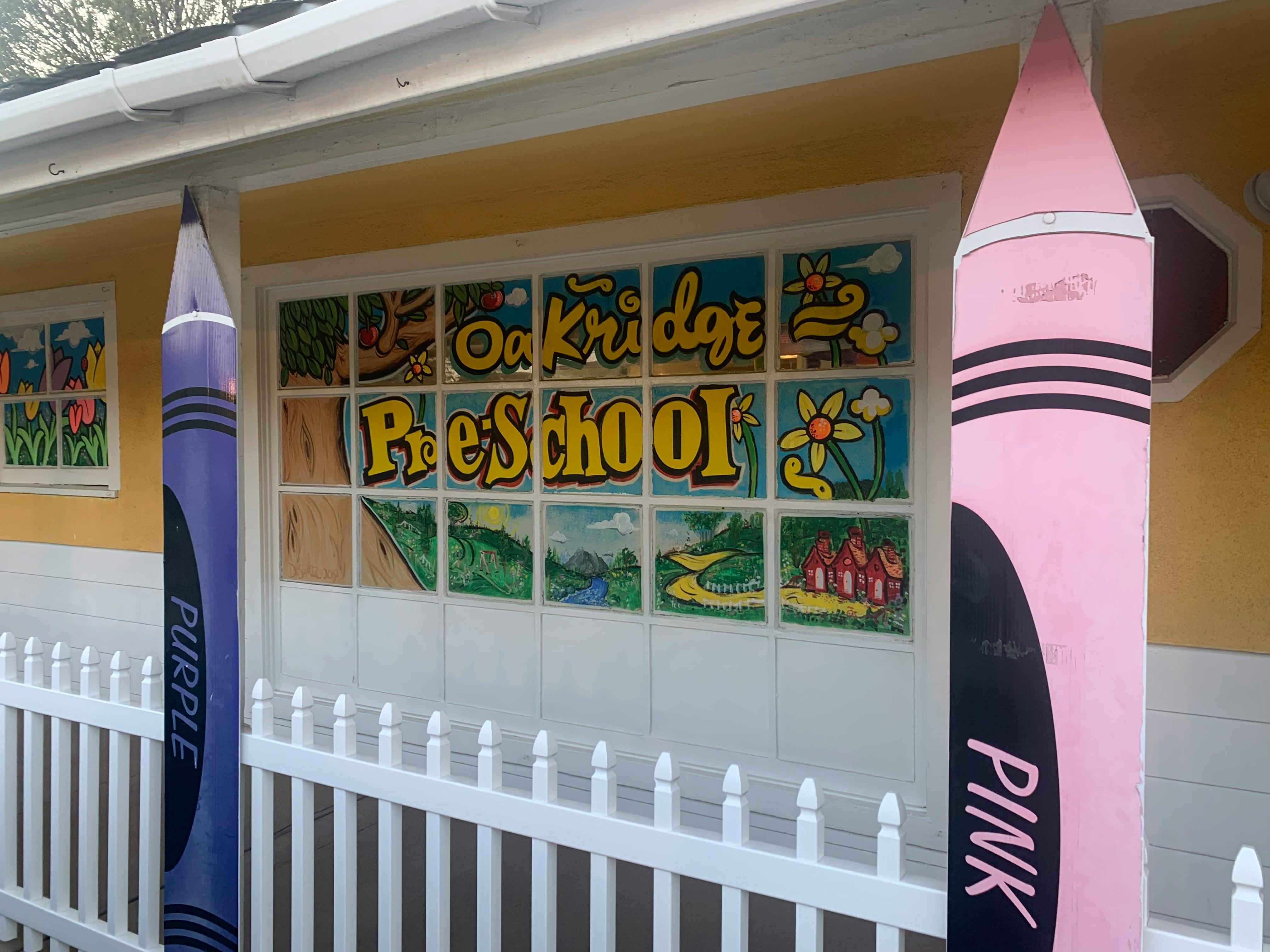 Oakridge Preschool sign with large purple and pink crayons