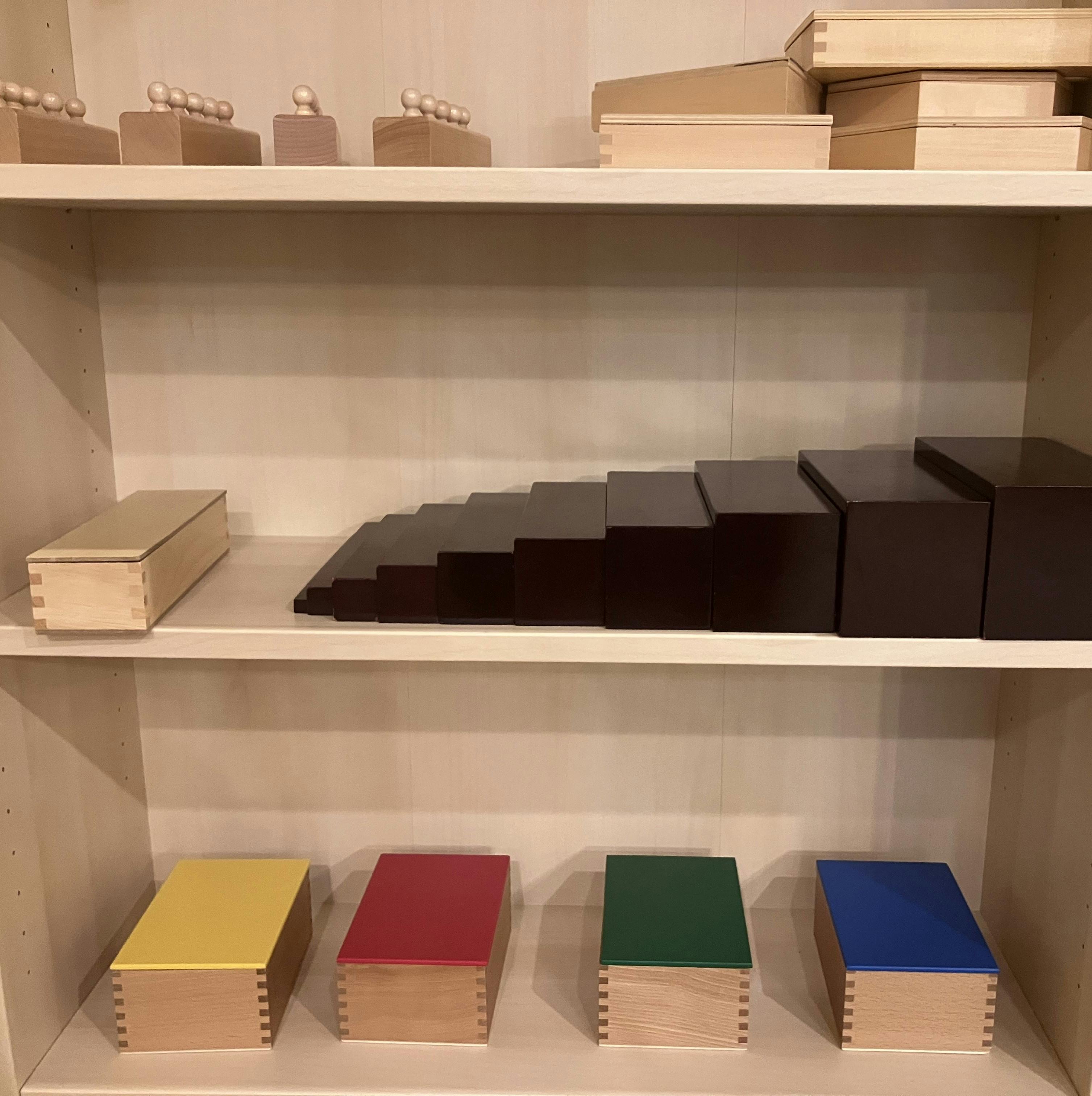 Shelves with wooden educational materials, including a brown stair and colored boxes