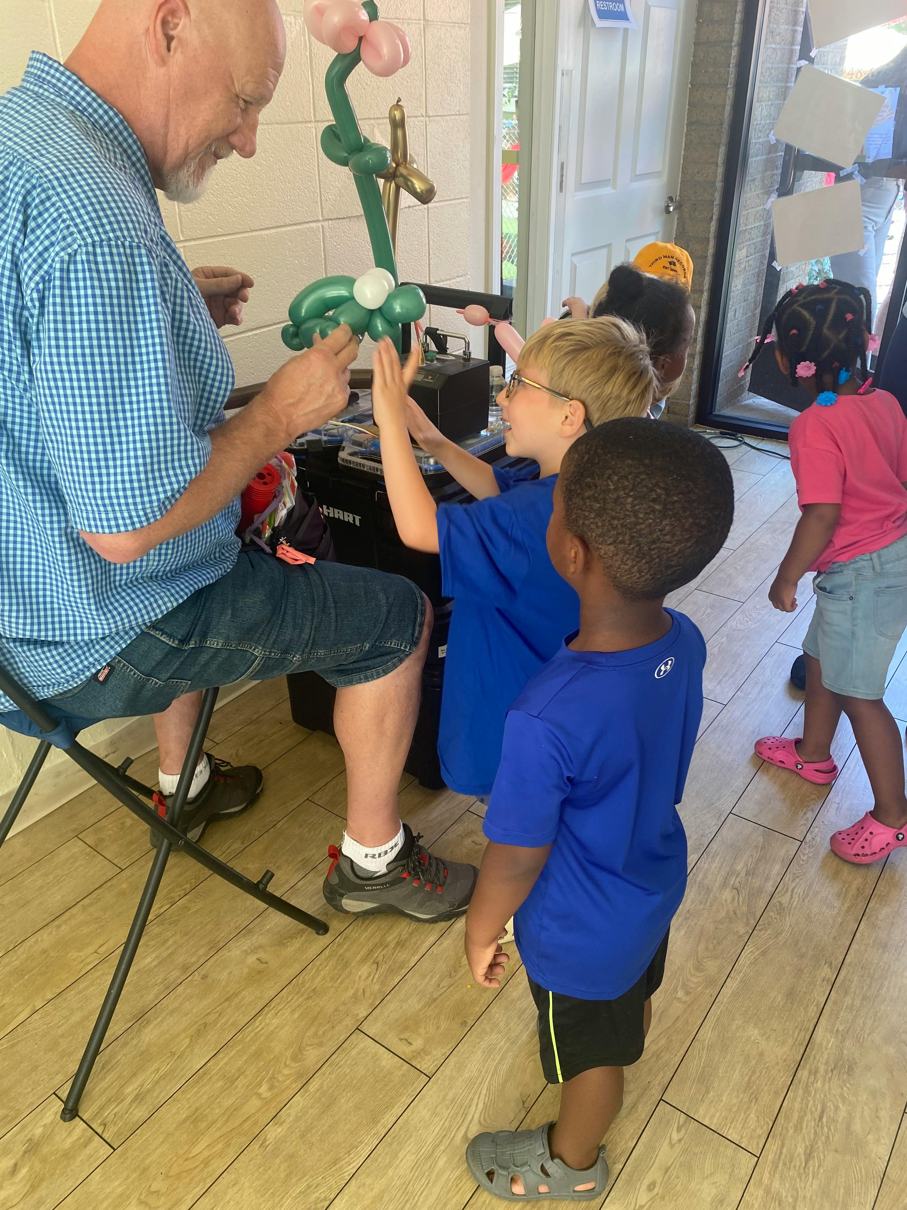 An adult making balloon animals for children