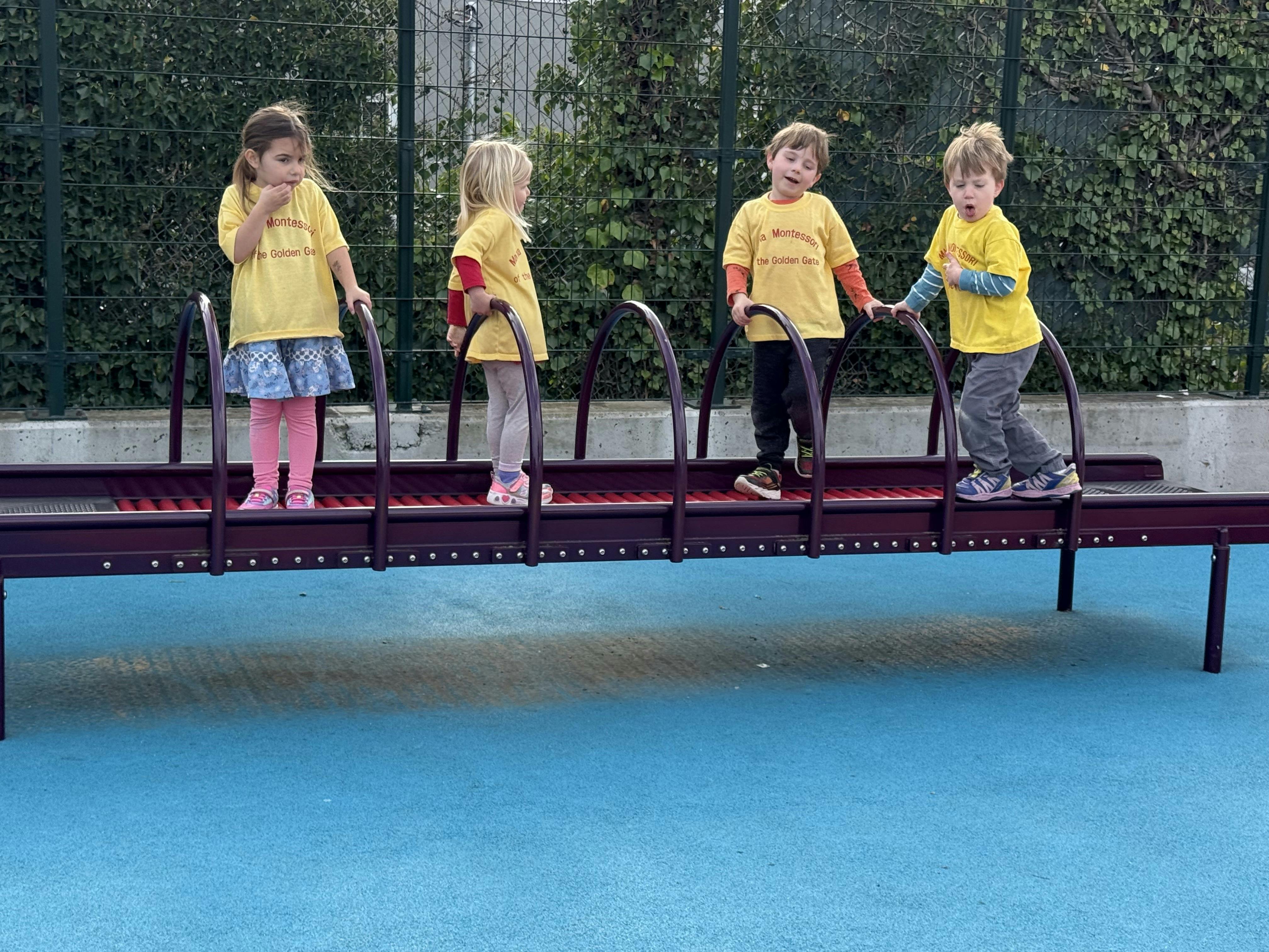 Four children standing on a playground climbing structure