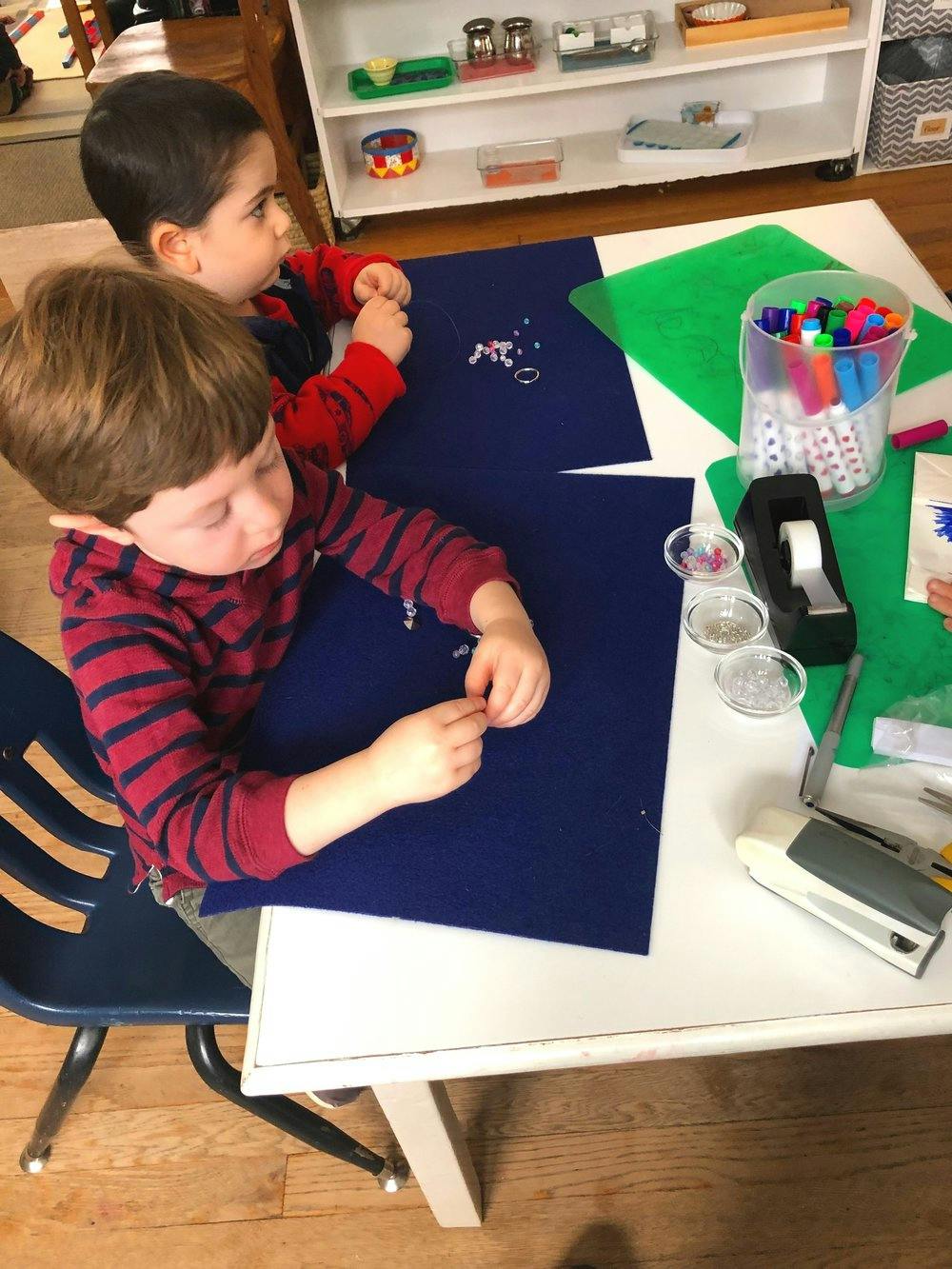 Two children at a table working with craft supplies