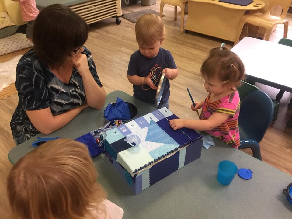 Adult and children at a table decorating a box