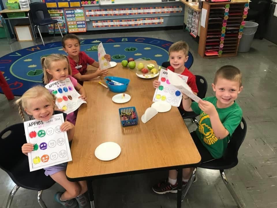 Children sitting at a table with papers and craft supplies