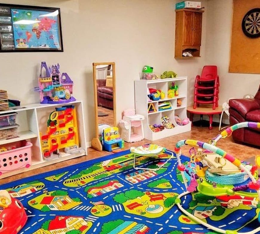 Playroom with a blue rug, shelves of toys, and a red couch