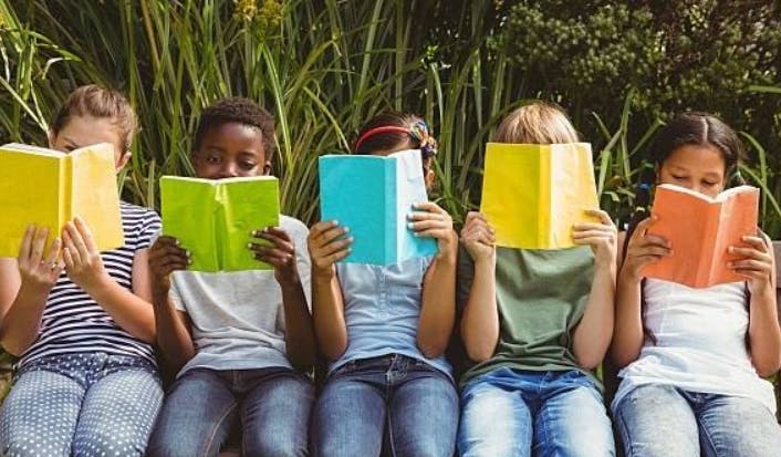 Five children reading books outdoors
