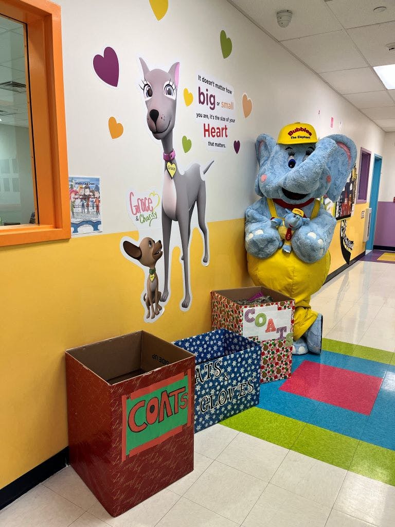 Hallway with cartoon dog cutouts, a blue elephant mascot, and donation boxes