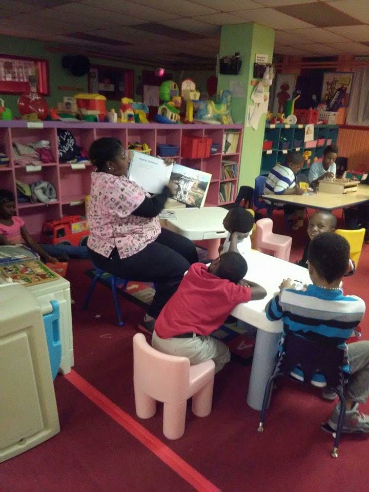 Person reading a book to children in a classroom