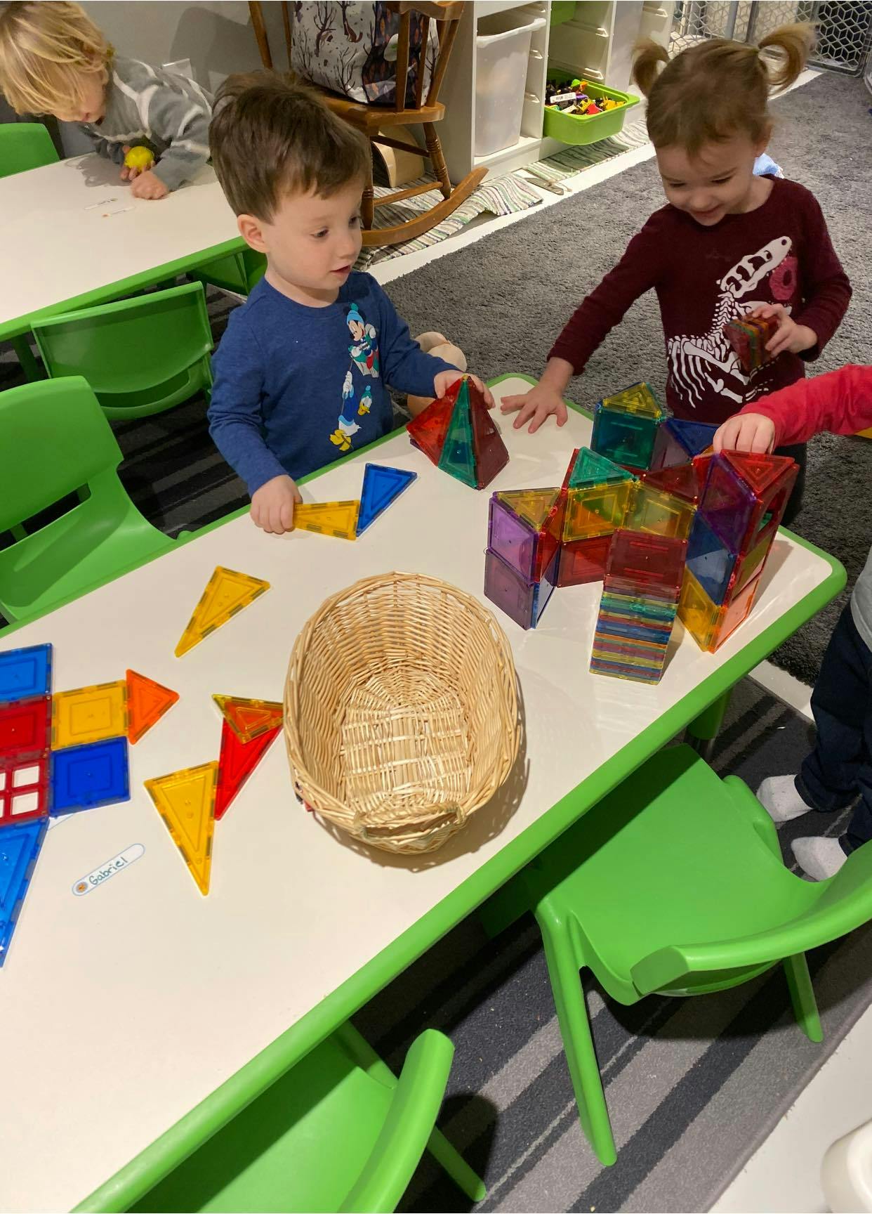 Children playing with colorful magnetic tiles at a table