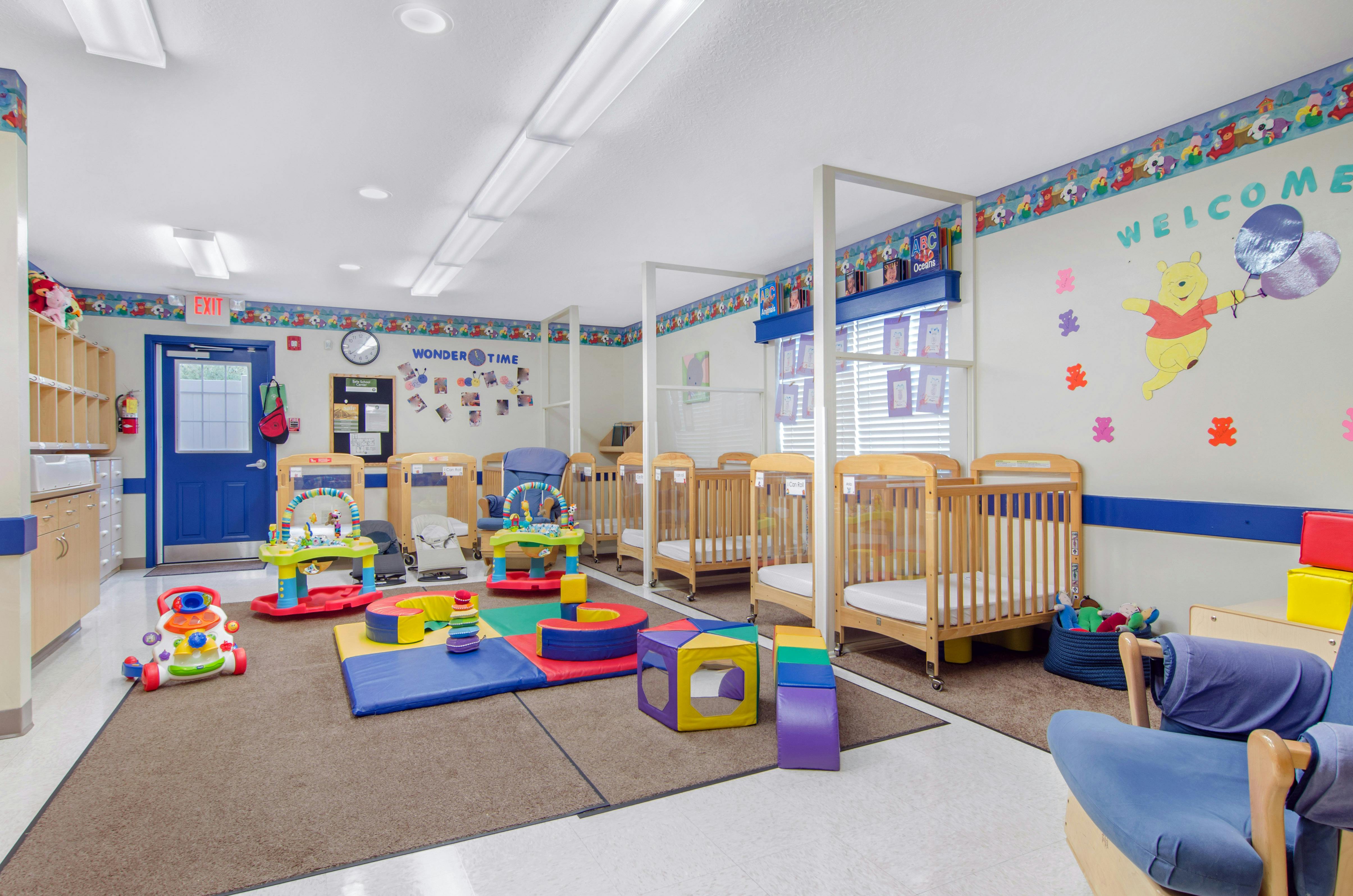 Baby nursery with multiple cribs, a play mat, and various infant toys