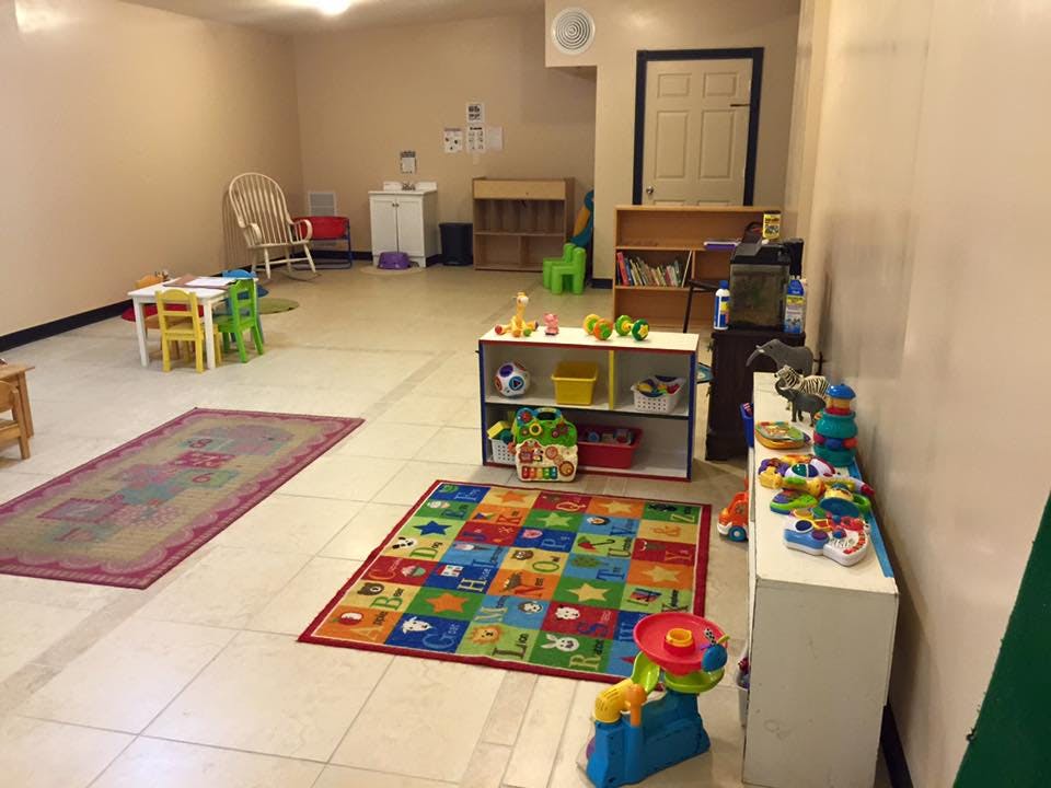 Playroom with colorful rugs, shelves of toys, and small tables