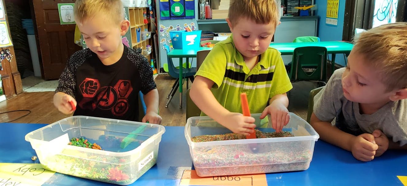 Three children playing with sensory bins