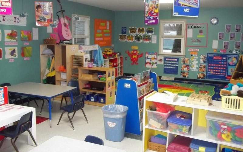 Classroom with tables and chairs, shelves, and colorful learning materials