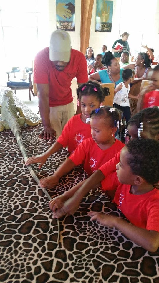 Person and children touching a large animal figure on a patterned table