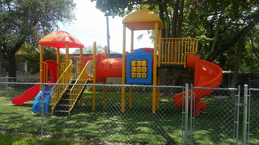 Playground with slides and climbing structures behind a fence