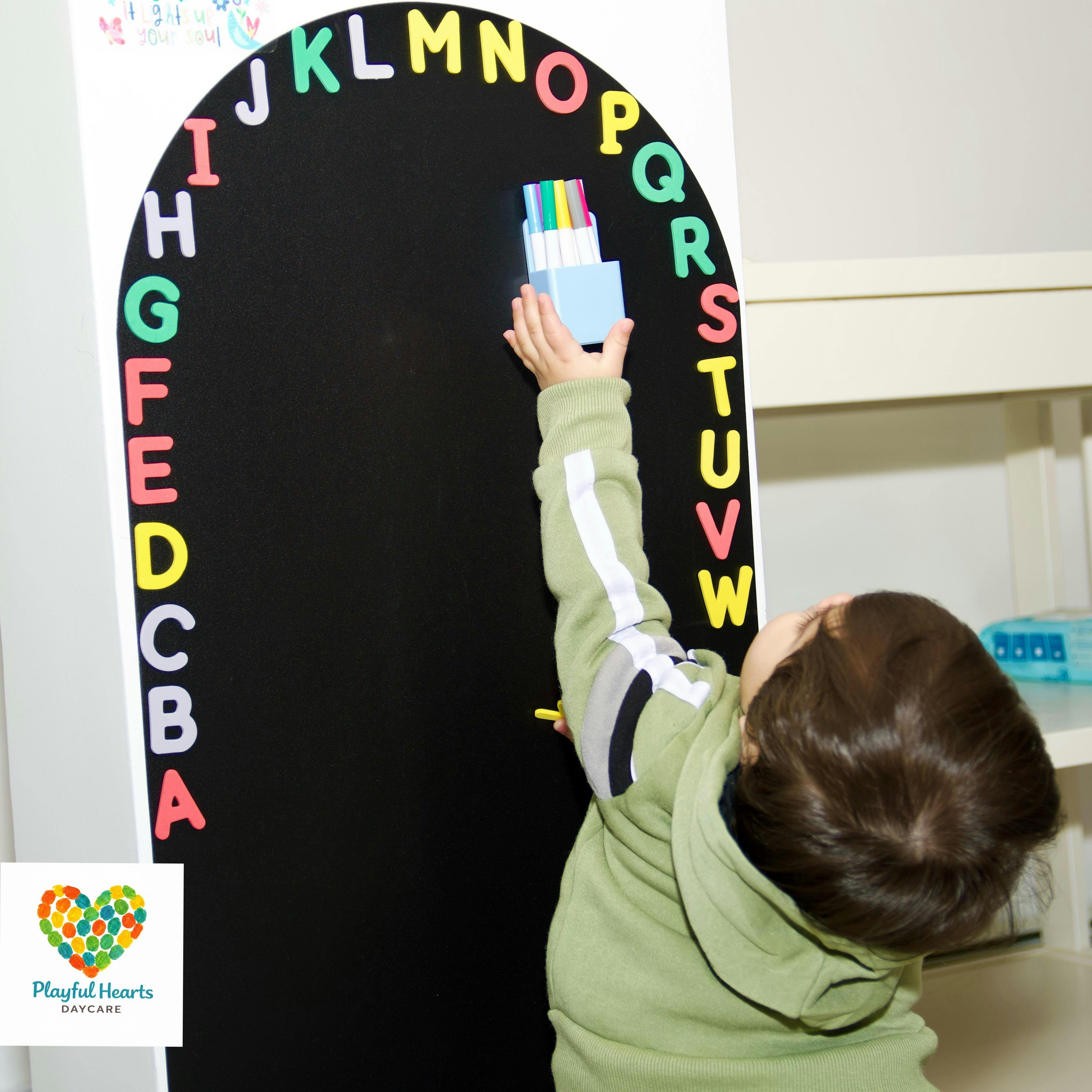 Child reaching up to place magnetic letters on a board