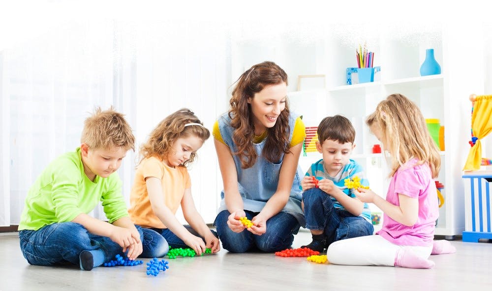 Adult and children playing with toys on the floor
