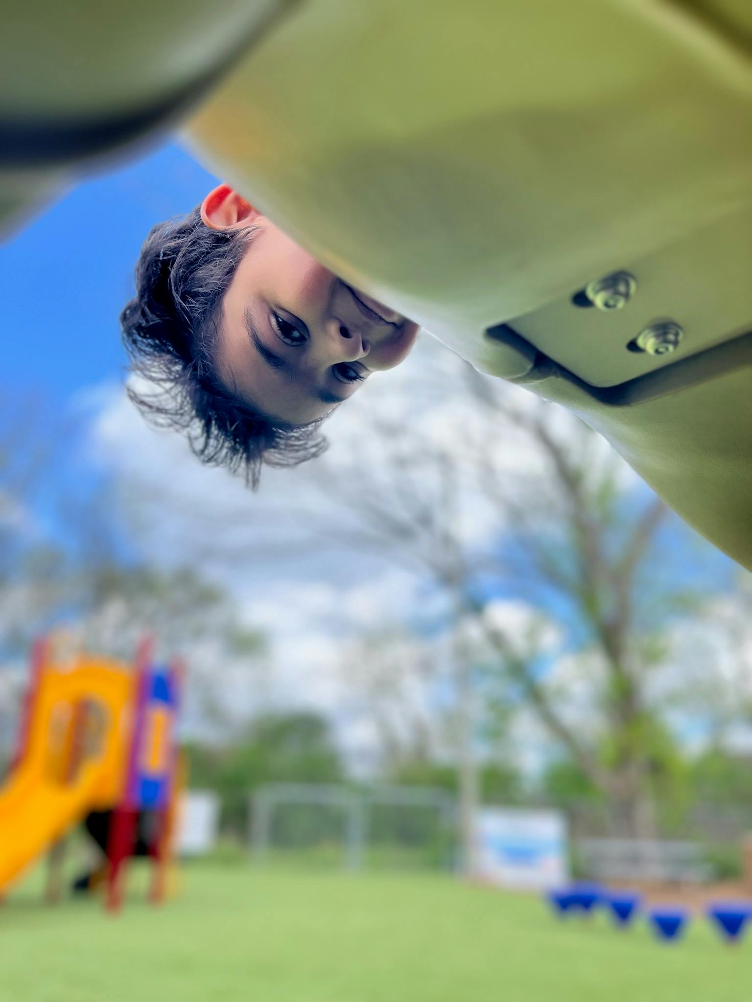 Person hanging upside down on playground equipment