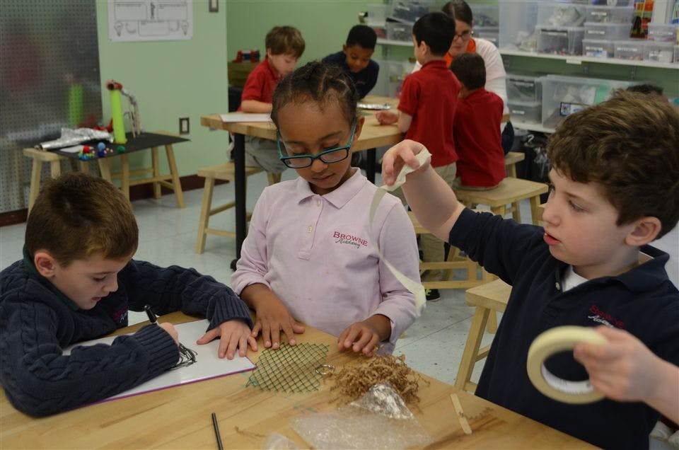 Three children working at a table in a classroom