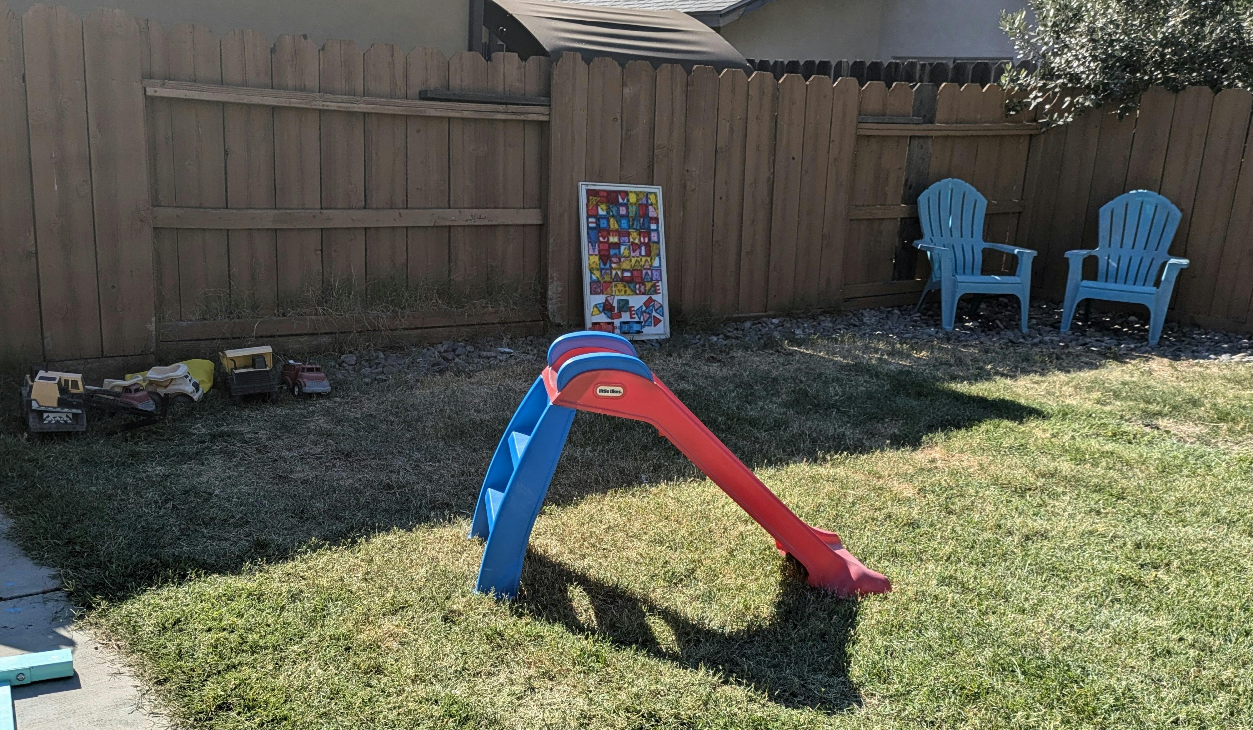 Red and blue slide in a grassy backyard
