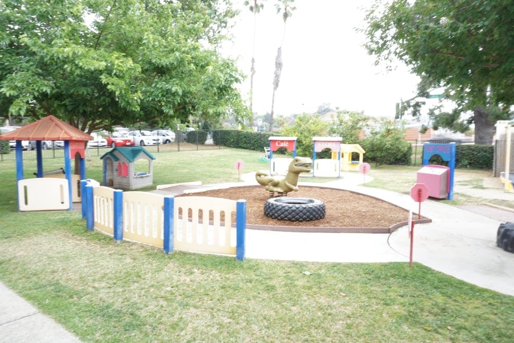 Outdoor playground with various play structures and a dinosaur