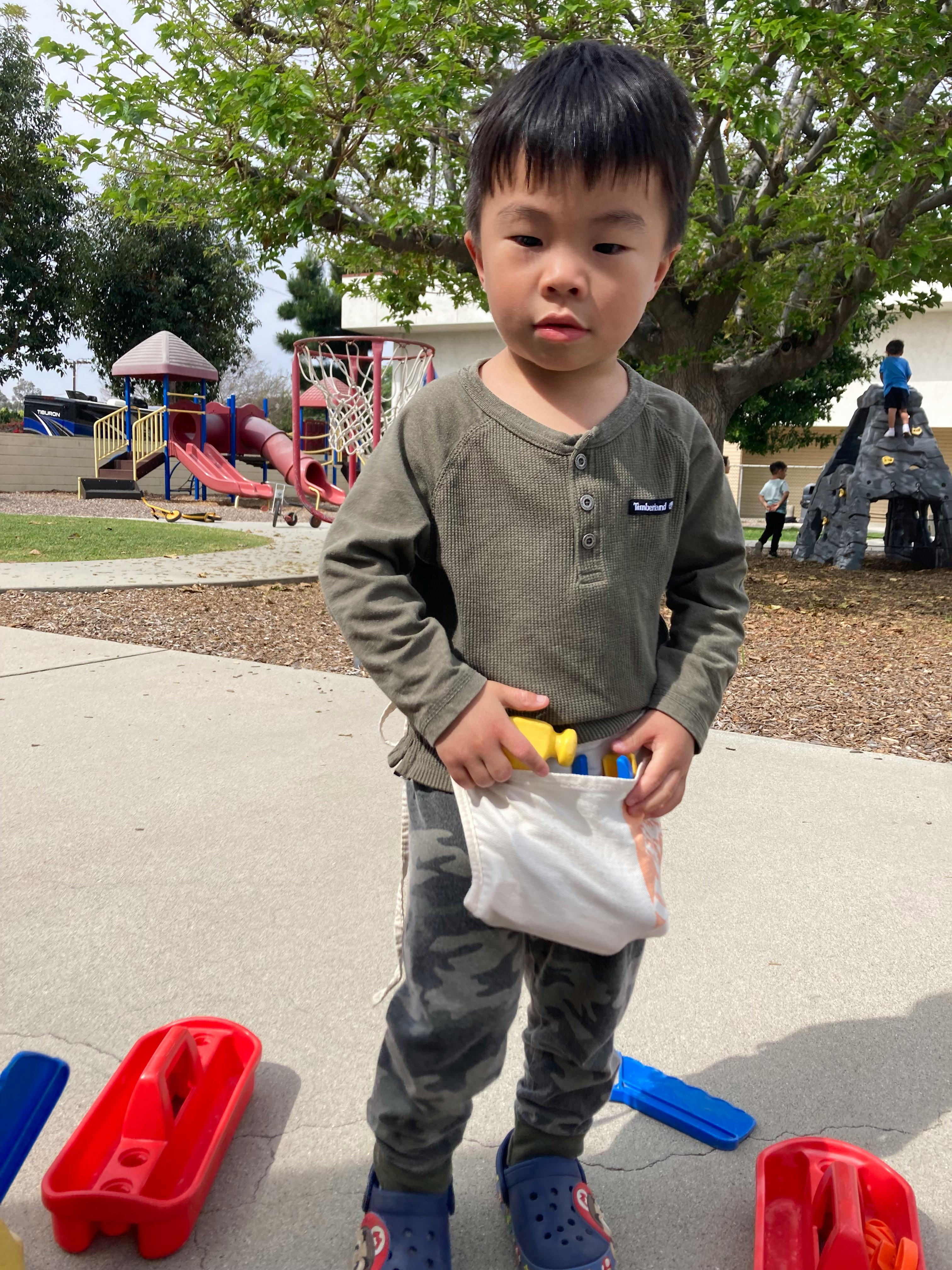 Child holding a bag of toys on a playground