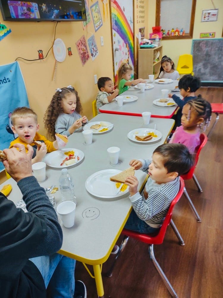 Children eating at a long table in a classroom
