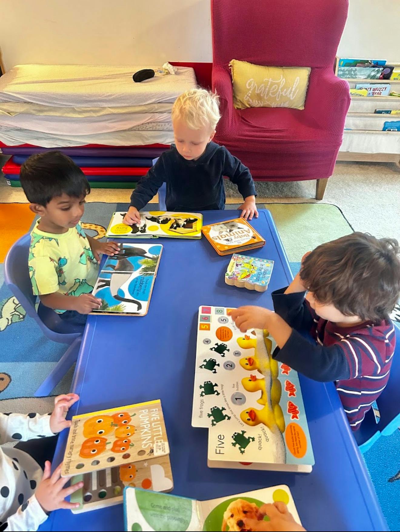 Four children sitting at a table looking at children's books