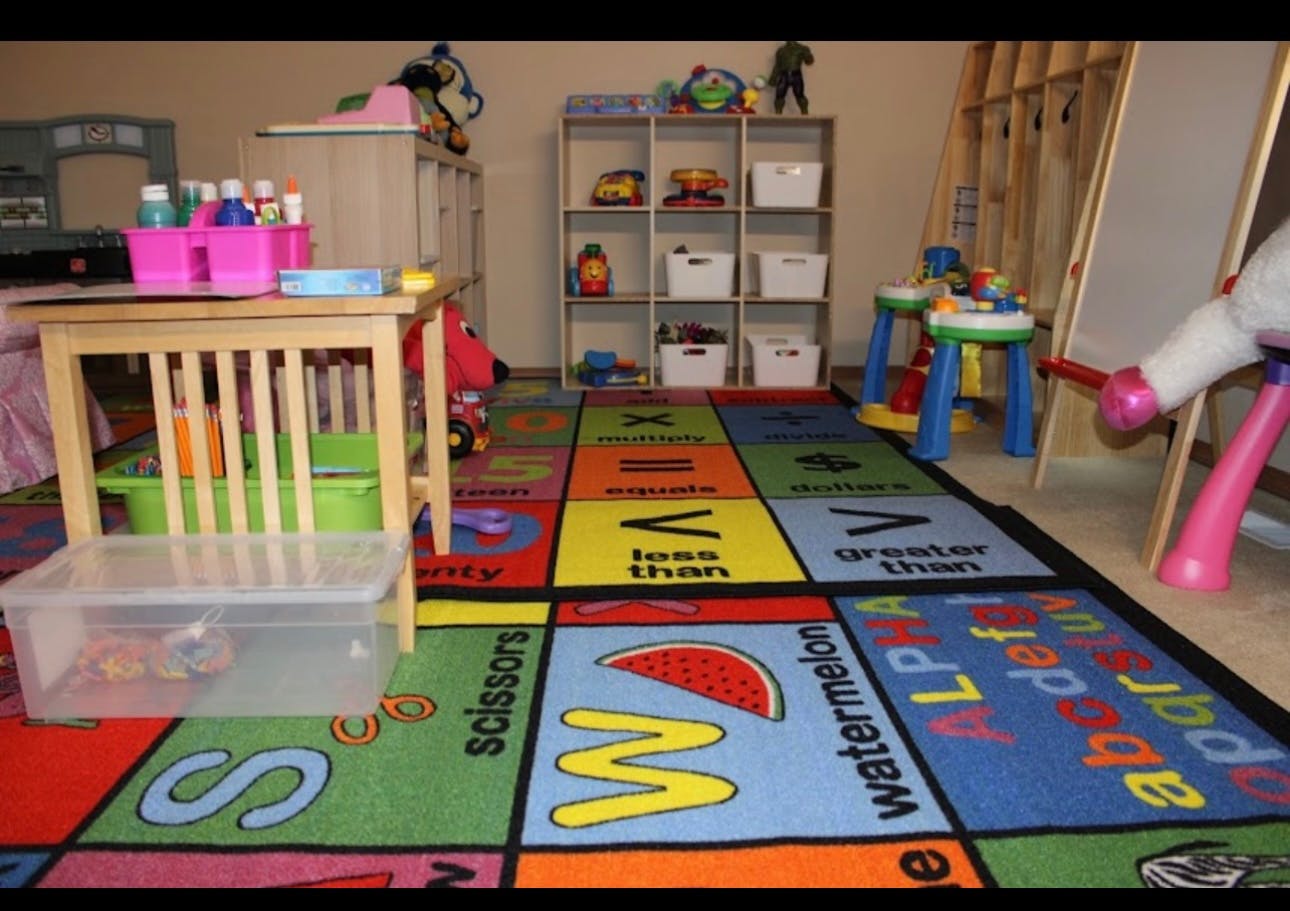 Colorful alphabet rug in a playroom with a small table and shelves