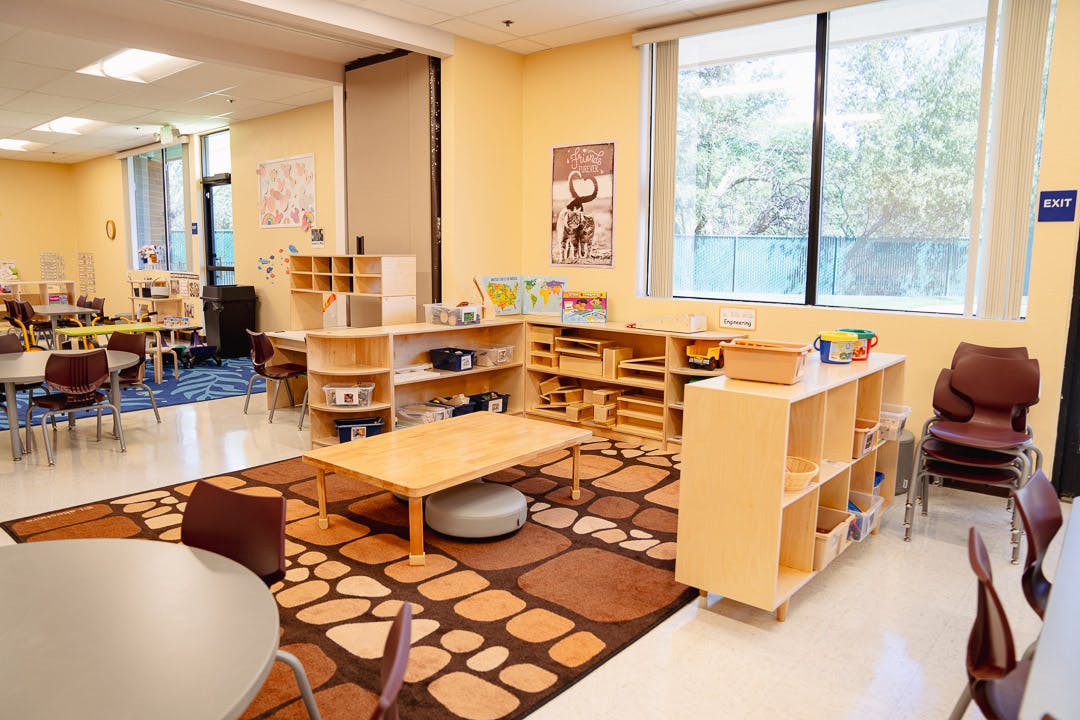 Classroom with tables, chairs, and shelves with learning materials