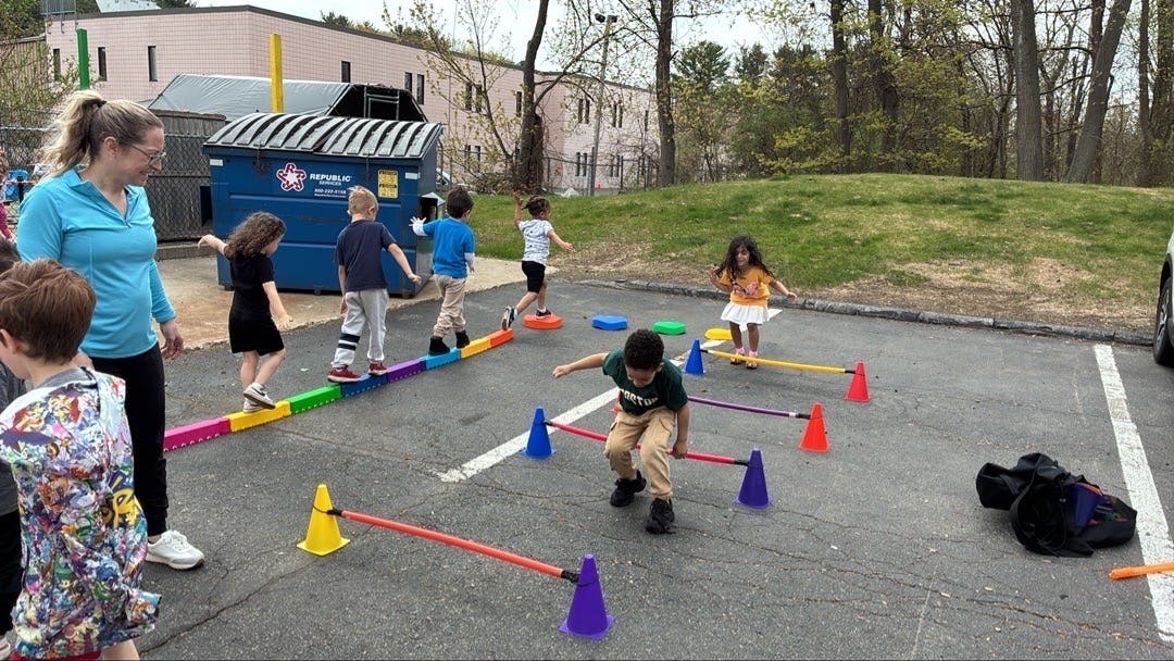 Adult supervising several children on an outdoor obstacle course