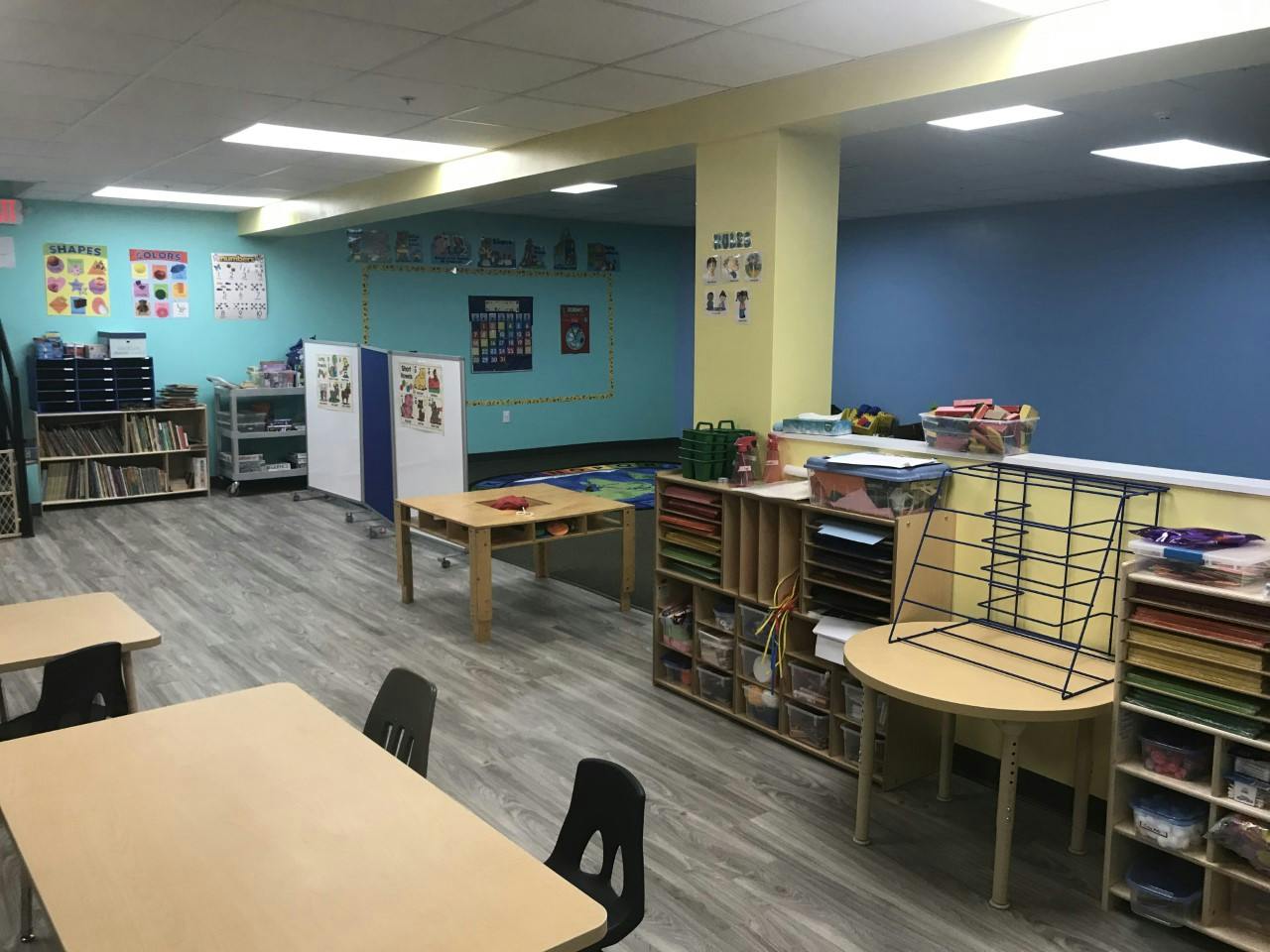 Empty preschool classroom with tables chairs and educational wall charts