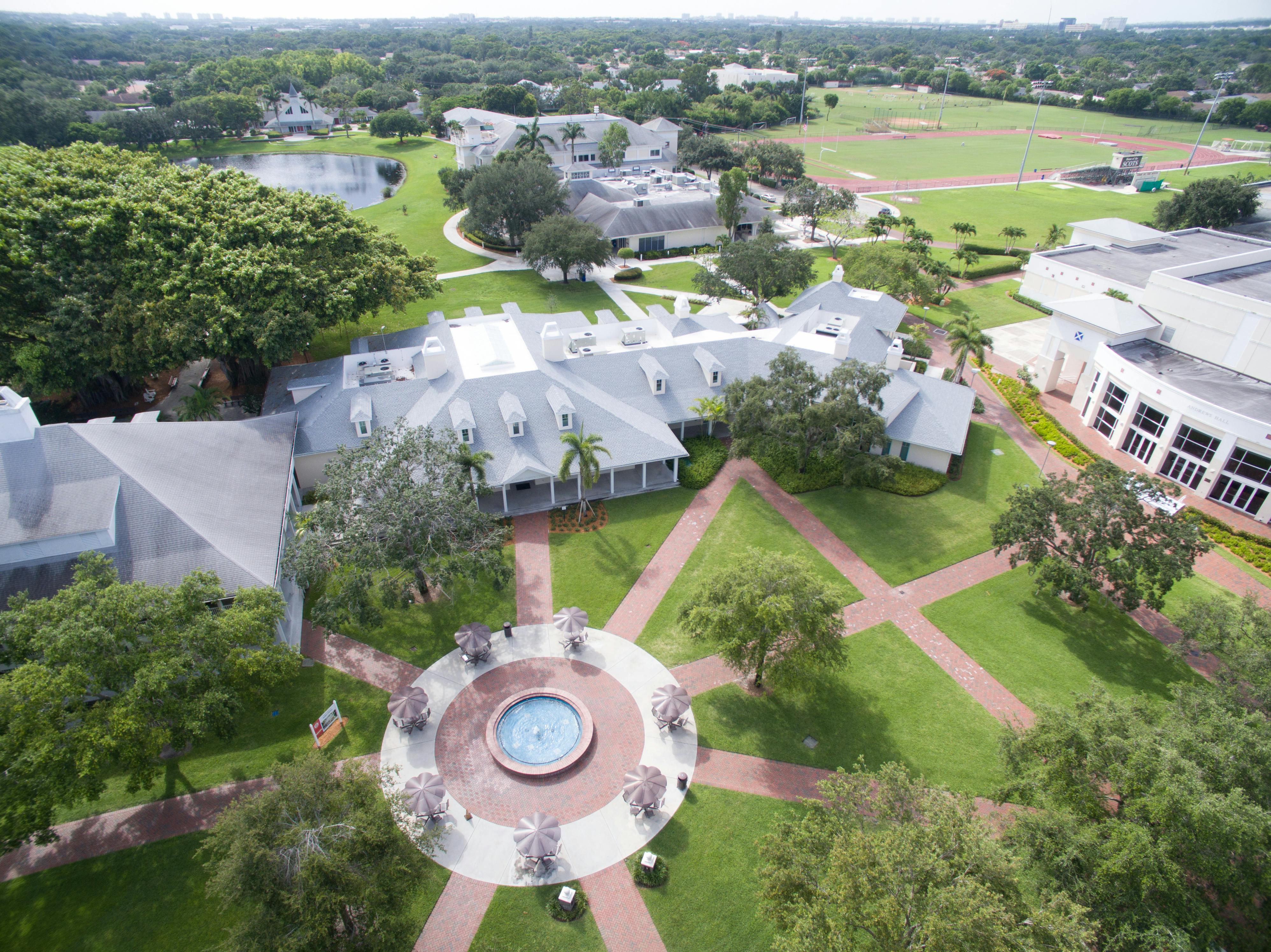 Aerial view of a campus with buildings, a fountain, and athletic fields