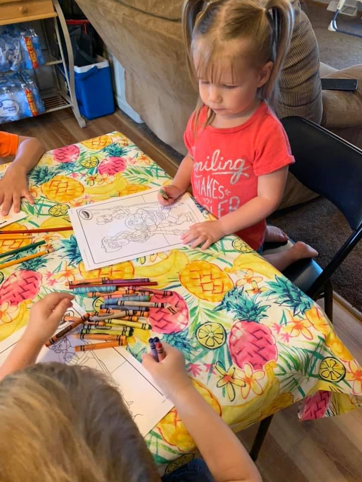 Child coloring at a table with crayons and another person