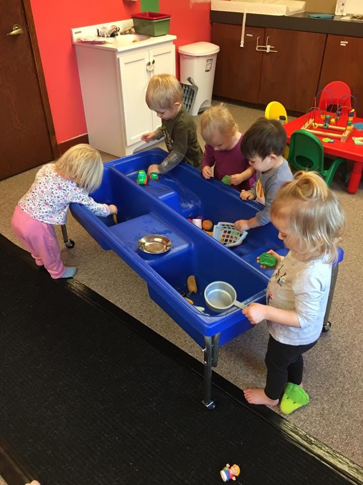Children playing at a water table in a classroom