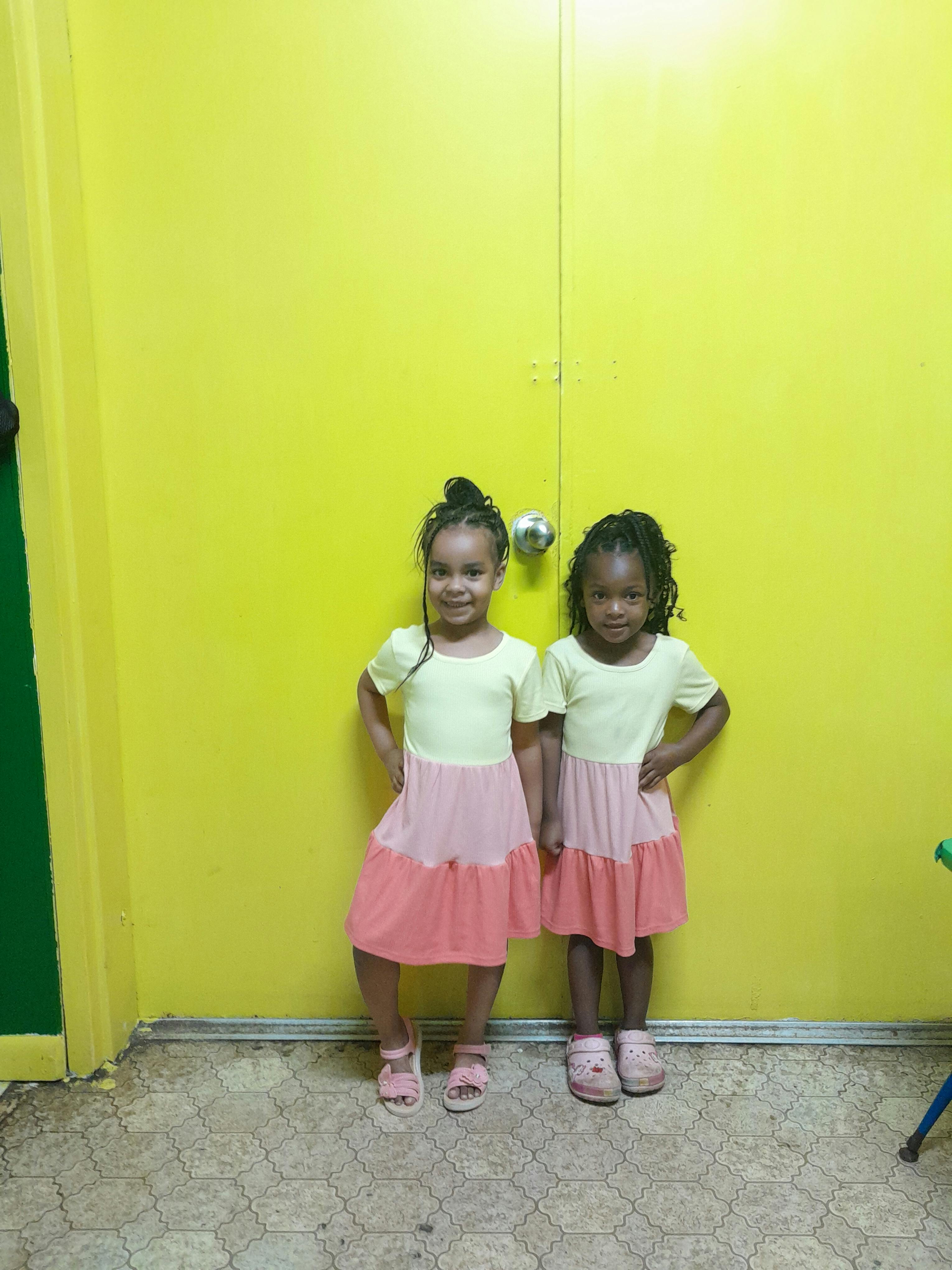 Two children standing in front of a yellow wall