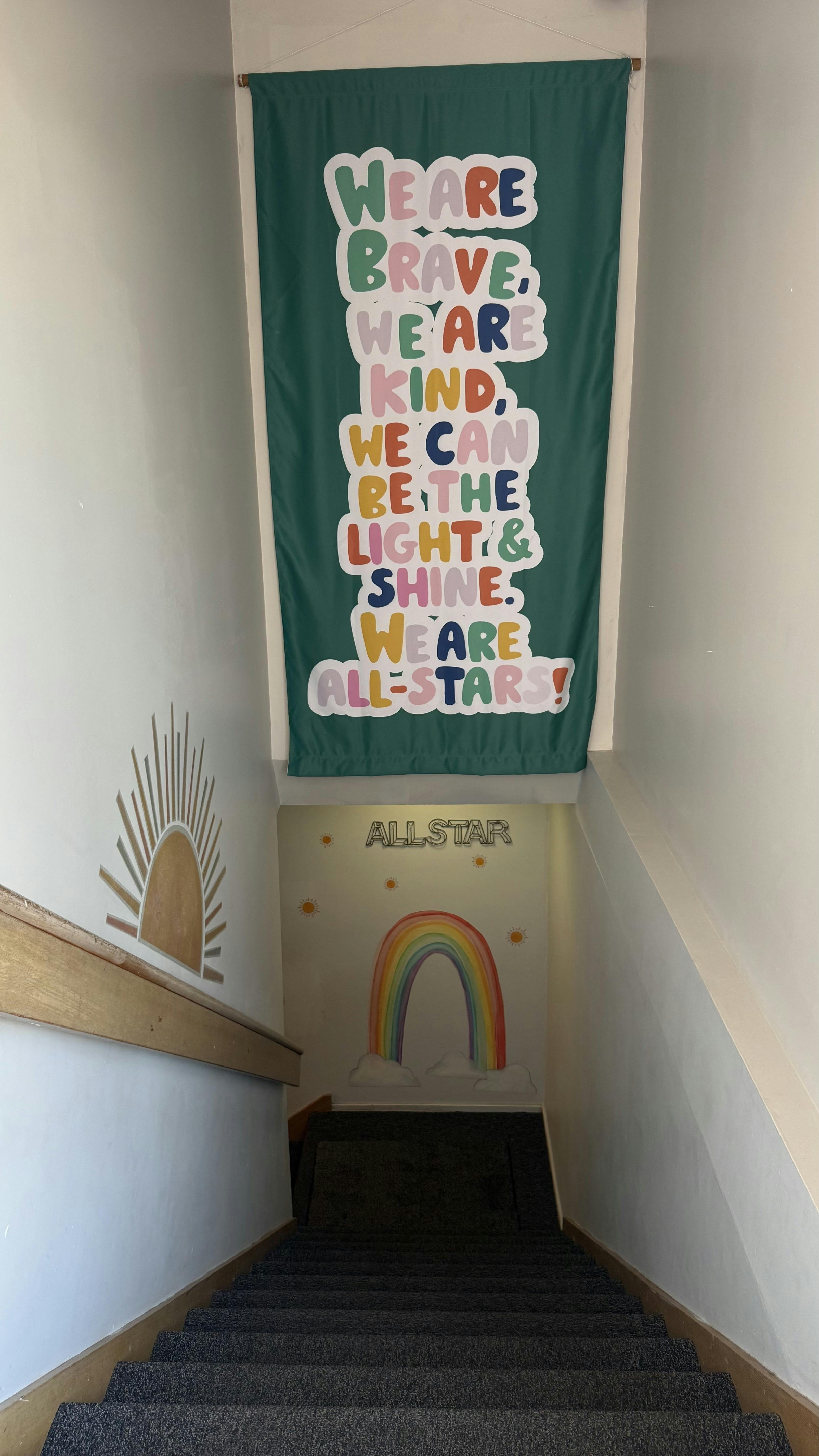 Staircase with a banner that reads "We are brave, we are kind, we can be the light & shine, we are all-stars!"