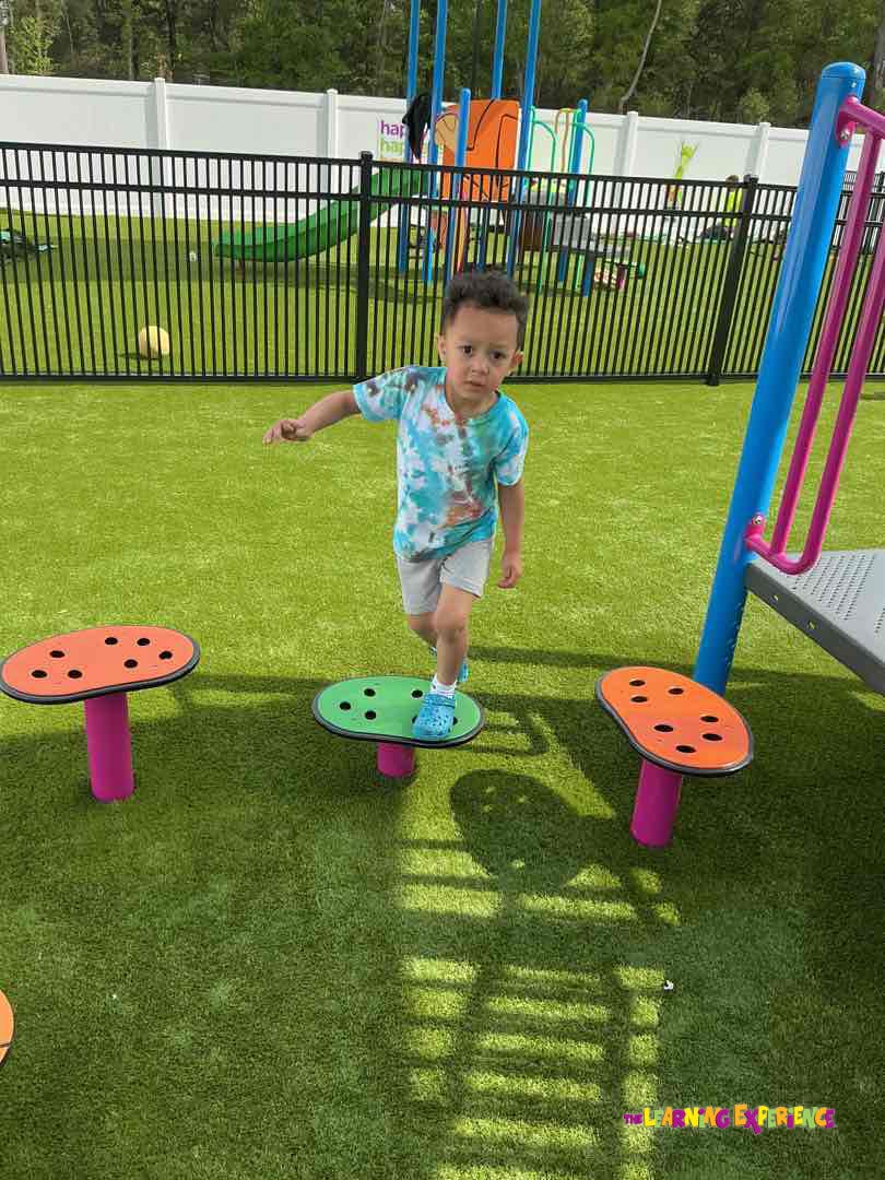 Child balancing on a mushroom stepping stone at a playground