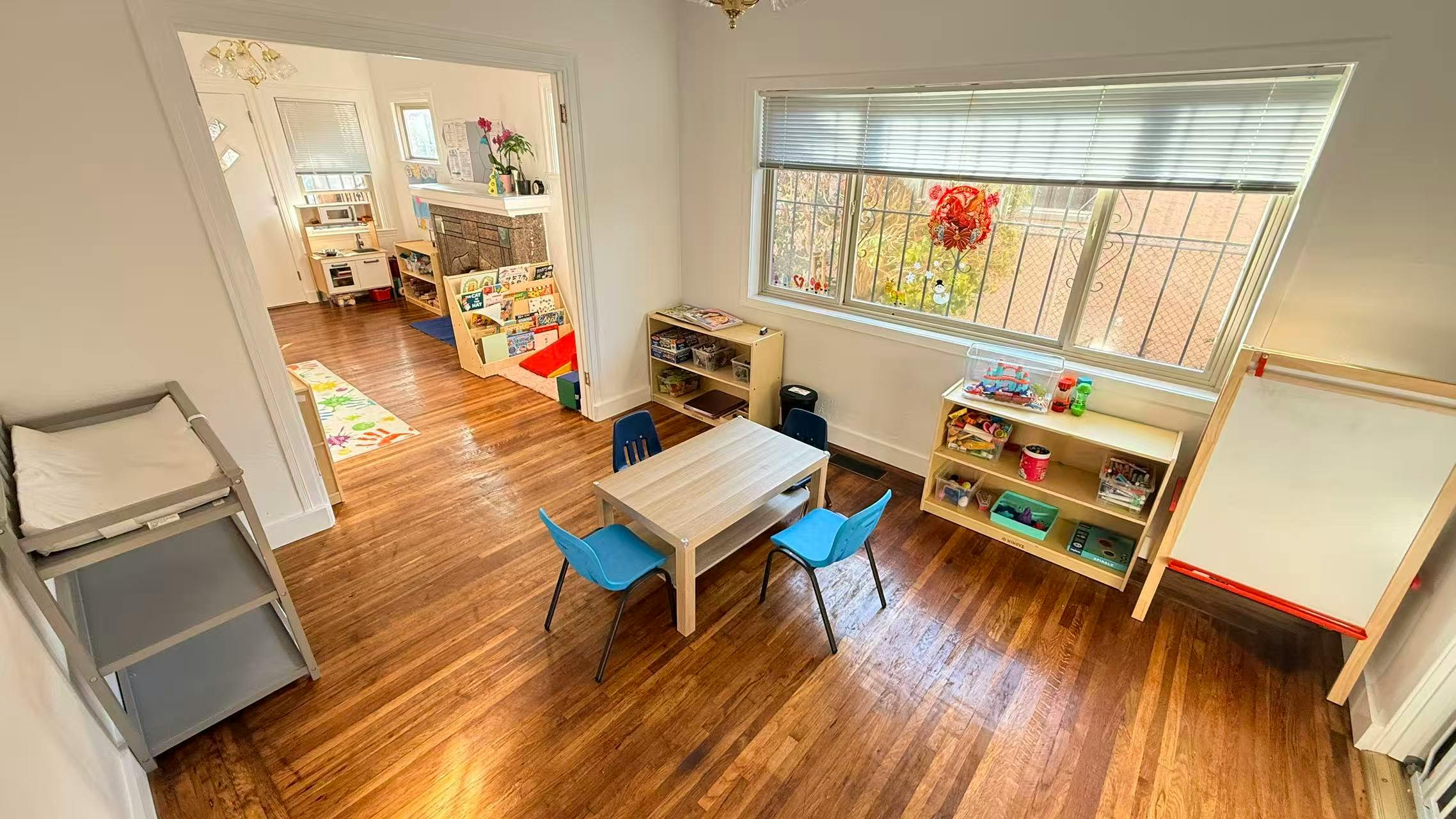 Playroom with a table and chairs, shelves with toys, and a changing table