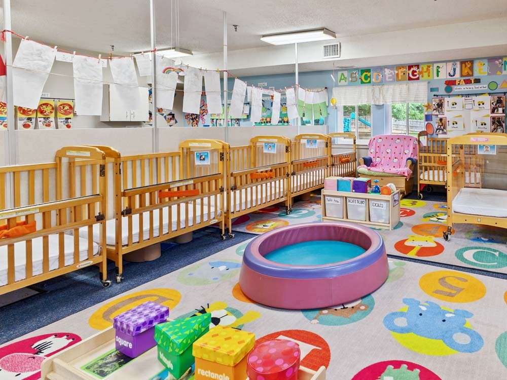 Cribs and play items in a brightly colored daycare room