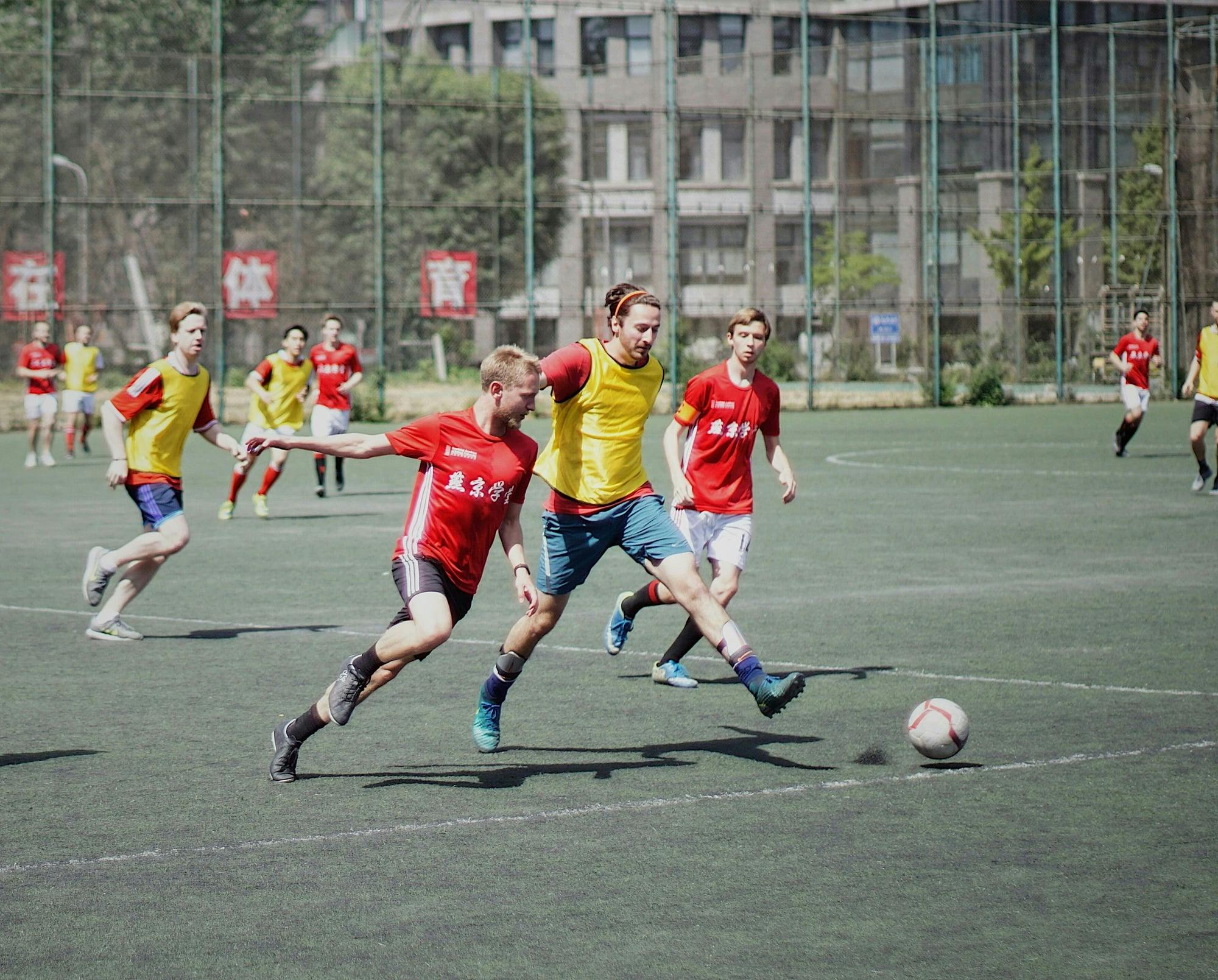 People playing soccer on a field, one person kicking a ball