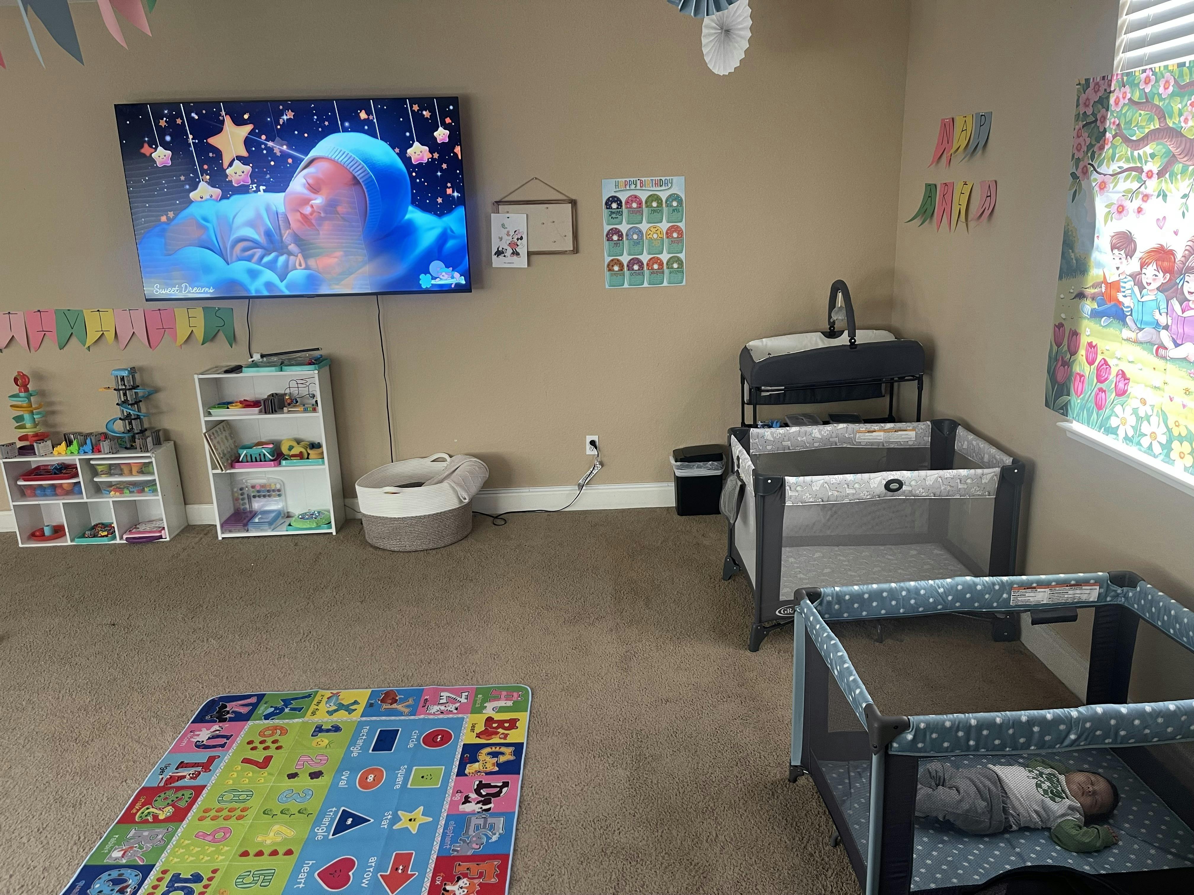 a large play area with two cribs and play mats, a TV playing content for children