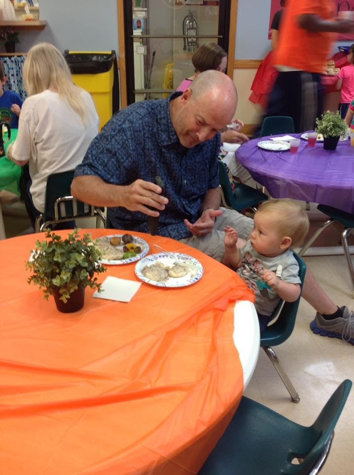 Adult person and child sitting at a table with plates of food