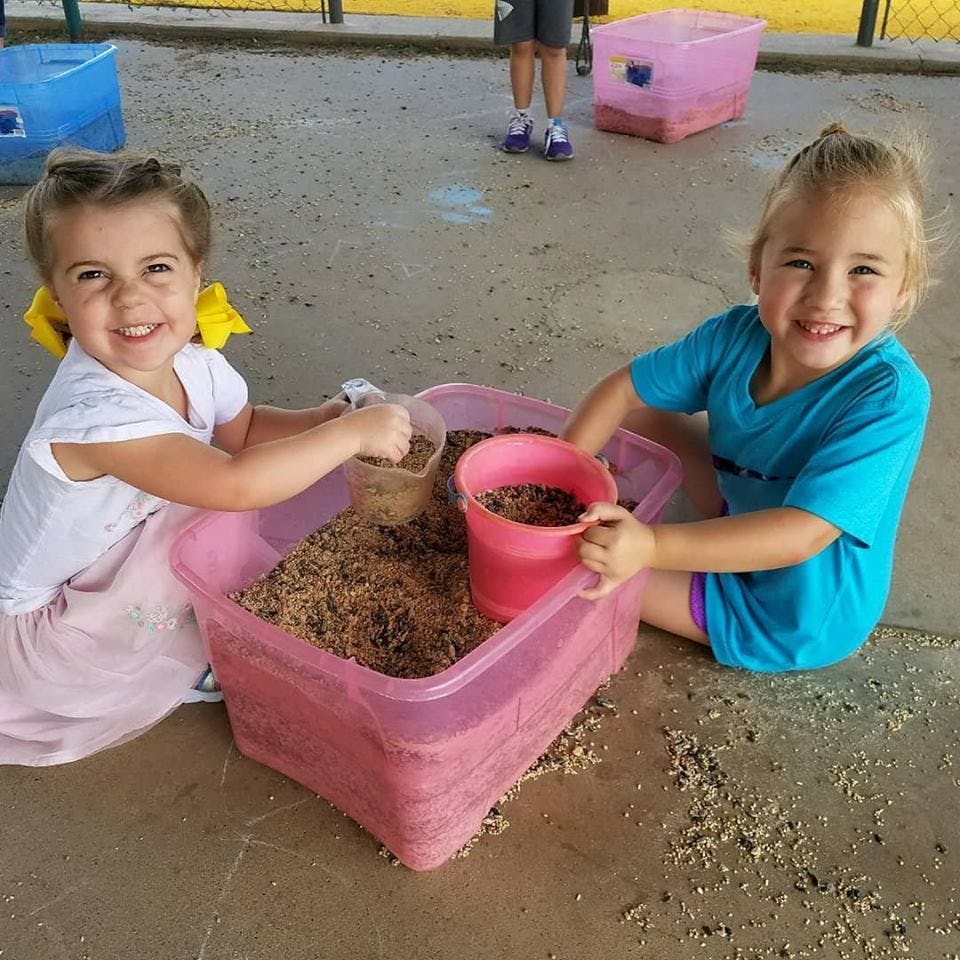 Two children playing with sand and buckets