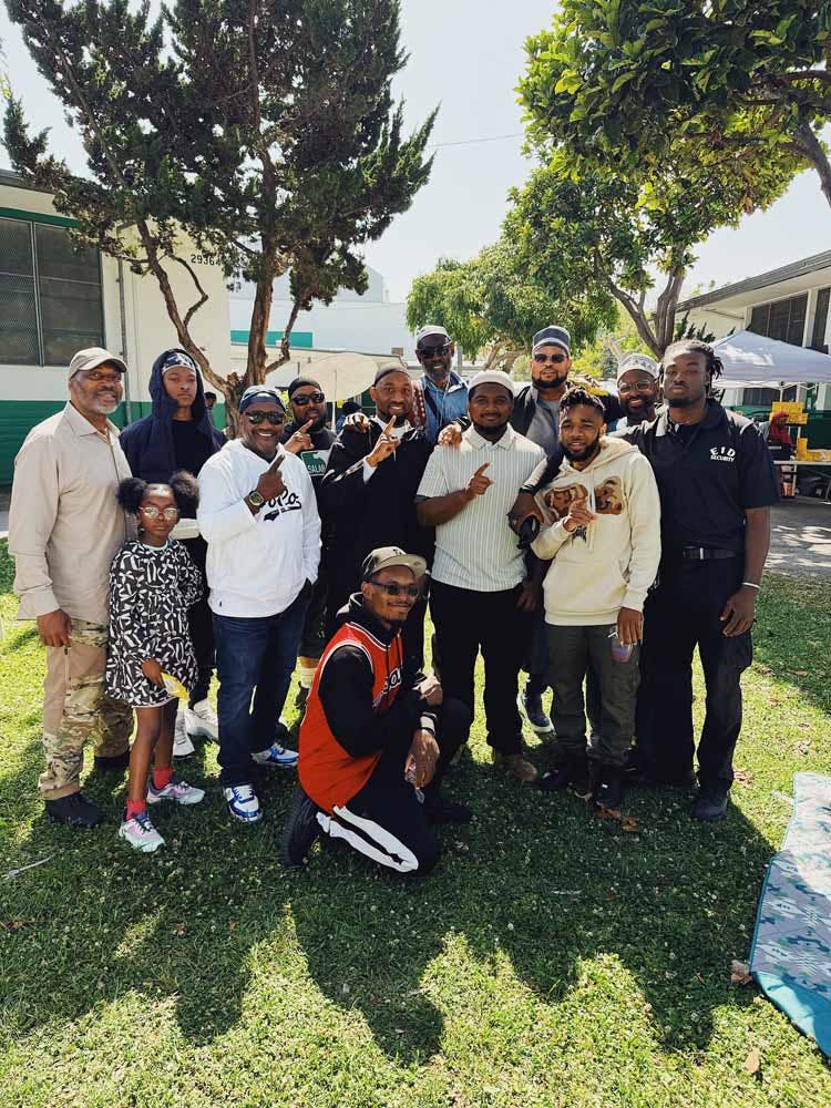 Group of people, including adults and a child, posing outdoors on grass