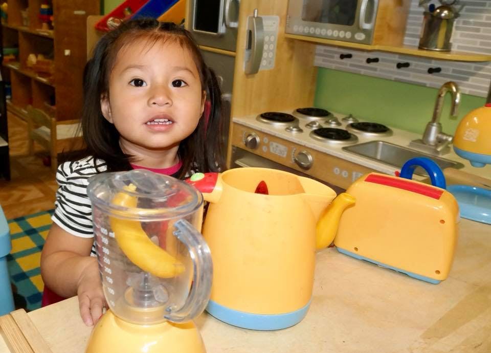 Child with toy blender and other kitchen toys