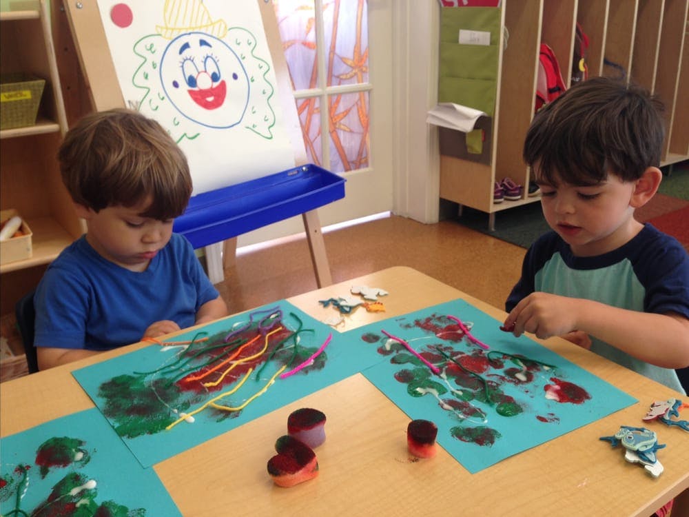 Two children painting at a table in a classroom